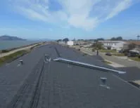 A view of a freshly completed roof with a coastal cityscape in the background, showcasing the workmanship of Ben's Roofing, Inc. in Oakland.