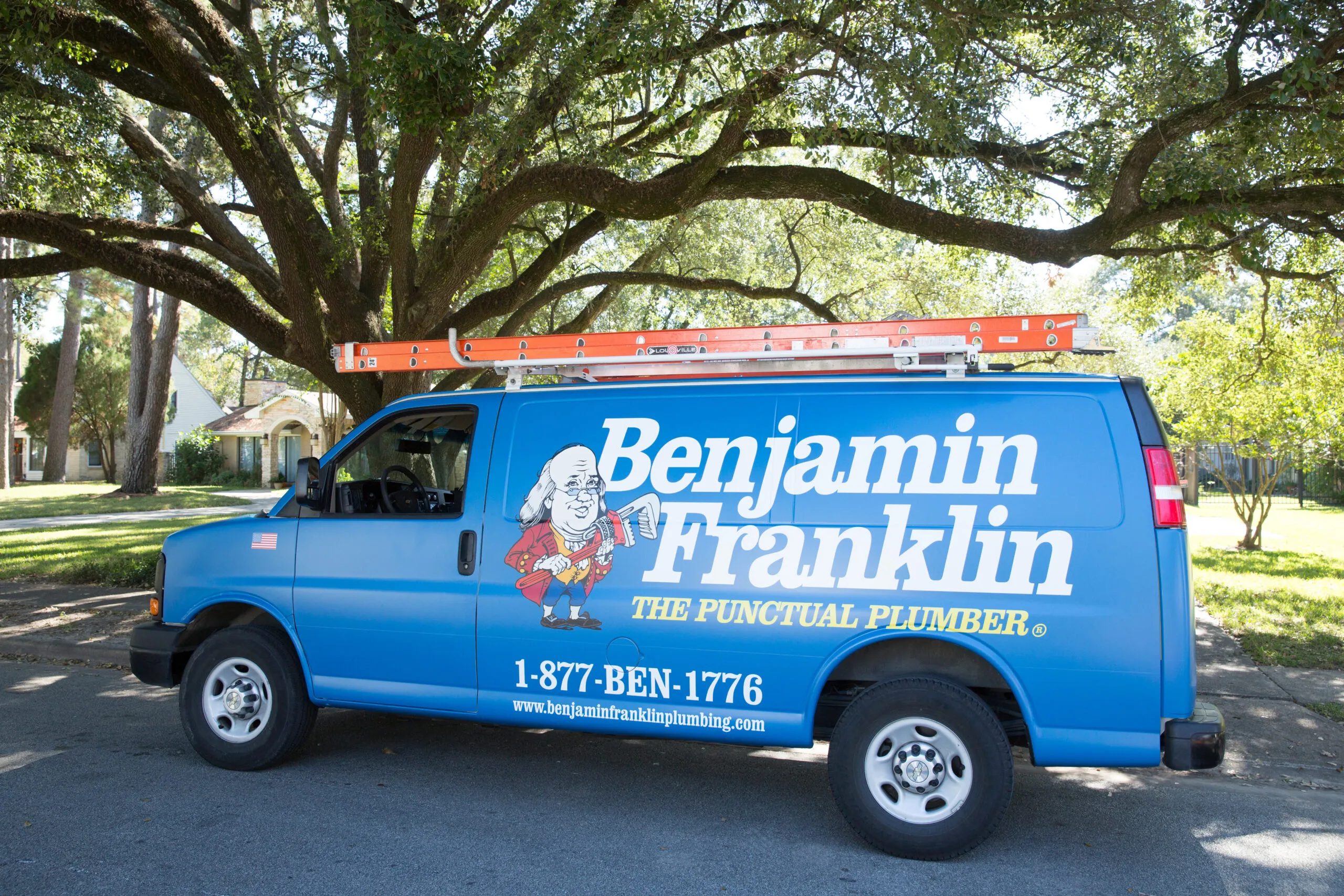 "A Benjamin Franklin Plumbing service van in Novato, featuring company branding and a ladder on top."