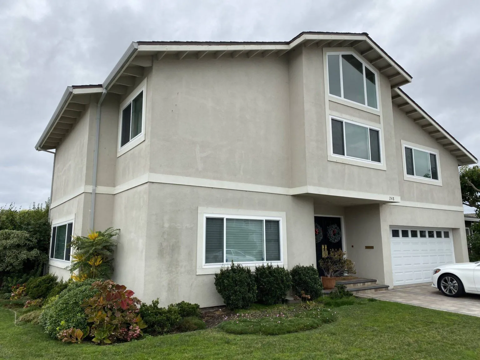 A two-story house with modern windows and landscaping, featuring a garage and driveway, renovated by Best Exteriors Construction, Inc. in Rocklin.