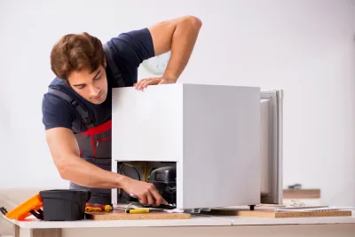 A technician from Bit Electrical Inc. in Daly City repairing a home appliance, focused and using tools.