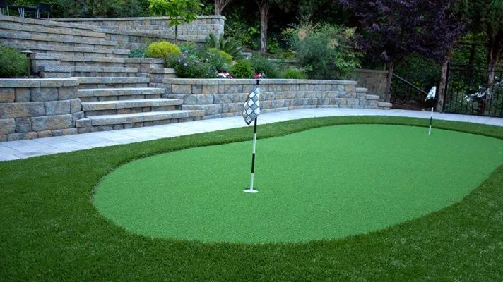 A landscaped backyard featuring a putting green, stone steps, and surrounding greenery, designed by Black Diamond Paver Stones & Landscape, Inc. in San Jose.