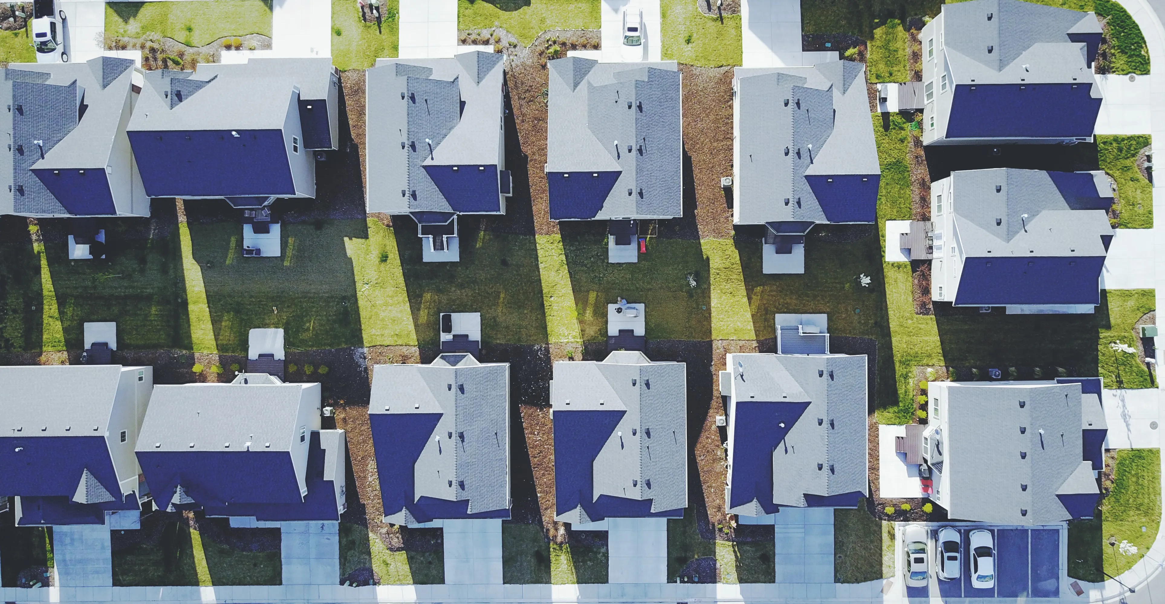 "Aerial view of a residential neighborhood with several houses lined up, showcasing neat lawns and driveways, representing the area served by Bluebird Termite in Burlingame."