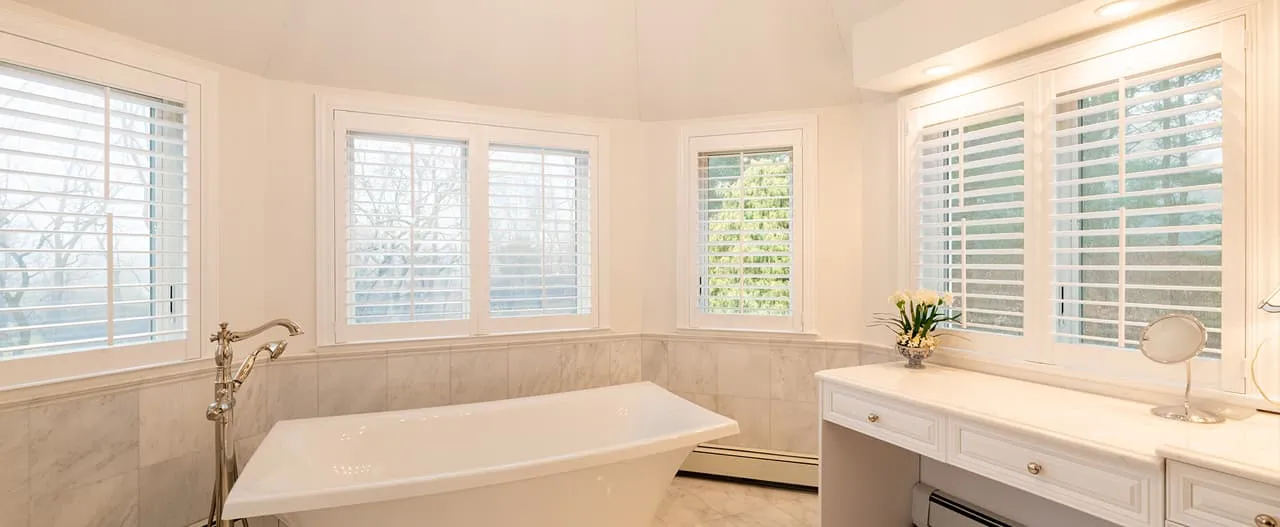 Luxurious bathroom in Rohnert Park featuring custom white shutters and a freestanding bathtub, installed by Budget Blinds of Central Marin and South Marin.