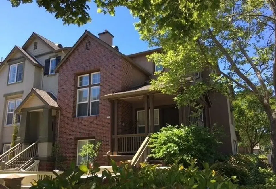 A charming multi-story brick and siding residential home with large windows, surrounded by trees and well-maintained greenery in San Jose.