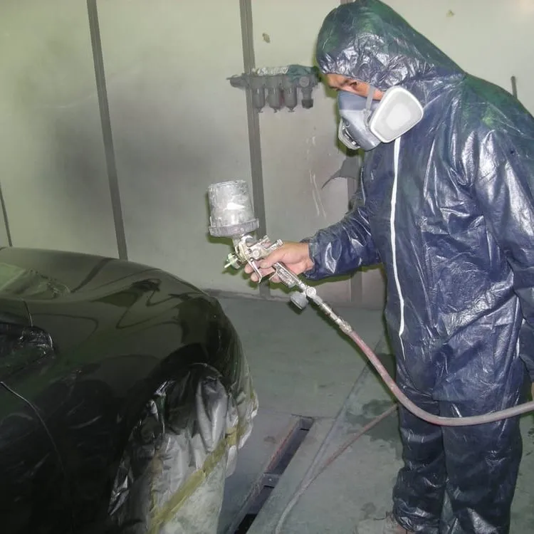 A technician in protective gear spray-paints a car in a workshop at Cal Auto Body in Daly City.