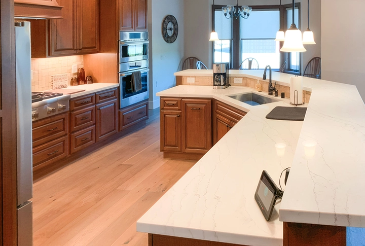 A modern kitchen with wooden cabinets and white marble countertops, showcasing the craftsmanship of Cal Pro Trim & Finish in Sacramento.