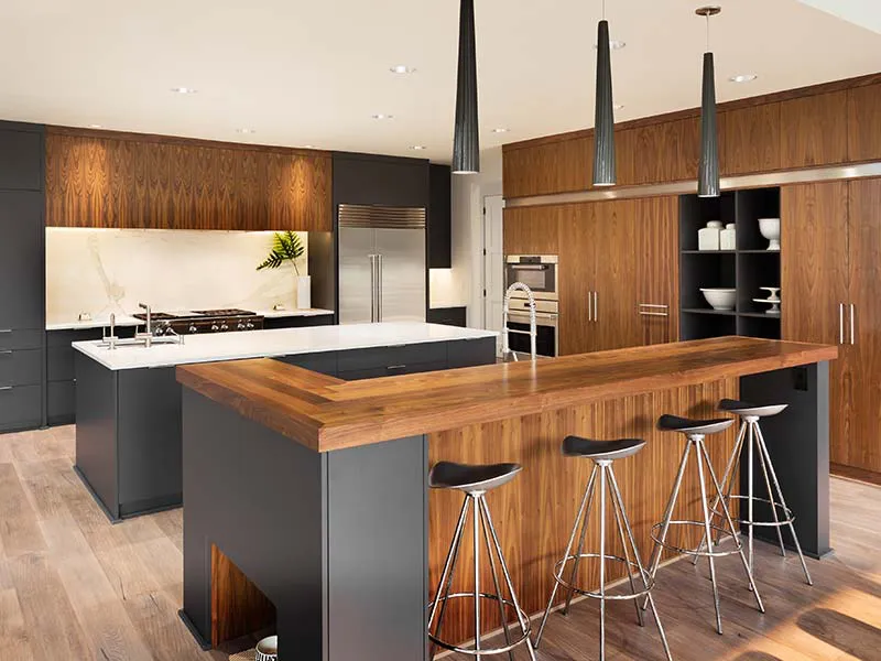 A modern kitchen featuring a wooden island with bar stools, sleek cabinetry, and stainless steel appliances, showcasing the craftsmanship of Cal Summit Builders in San Rafael.