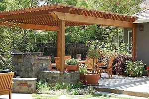 A wooden pergola and stone patio with seating, constructed by California Fencing Company in San Rafael.
