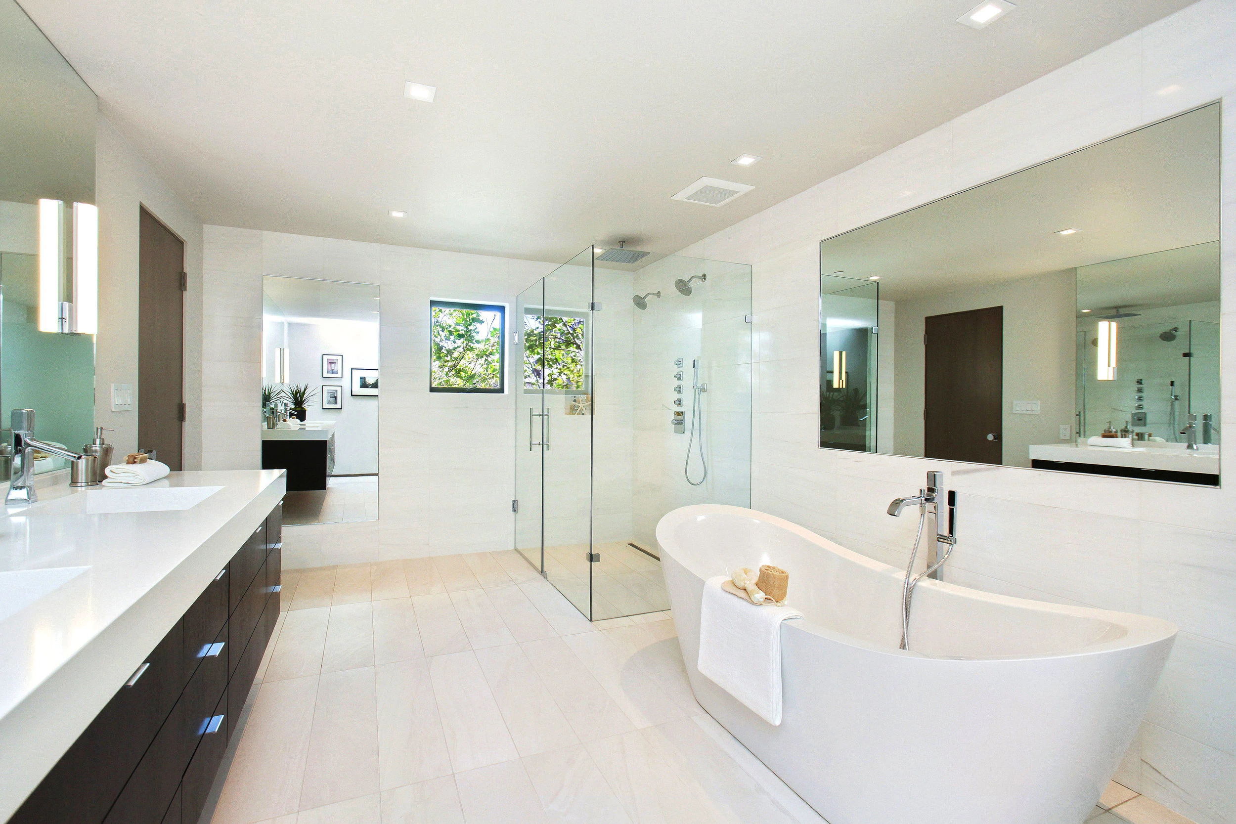 "A modern bathroom with a freestanding bathtub and glass shower enclosure, designed by California Shower Door Corporation, featuring sleek surfaces and natural light in San Francisco."