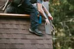 A person from Capstone Roofing, Inc. working on a shingle roof in Santa Rosa, focusing on precise shingle alignment.
