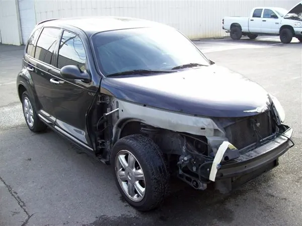 A partially disassembled dark-colored car in need of repair is parked outside on a concrete surface, highlighting the expertise required at Carreras Autobody Inc in Healdsburg for restoration.