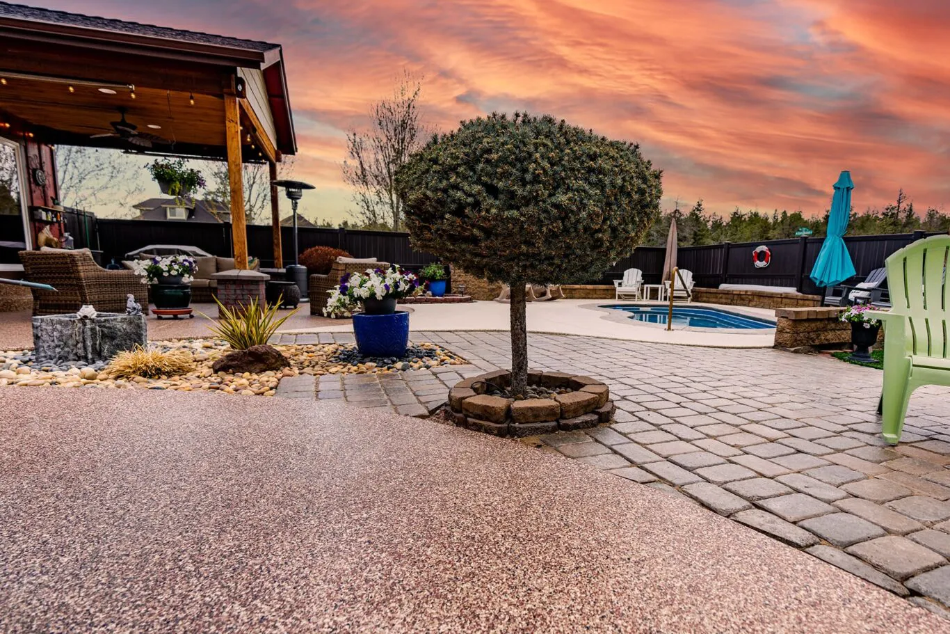 Outdoor patio area with a tree, potted plants, seating, and a pool at sunset in San Jose.
