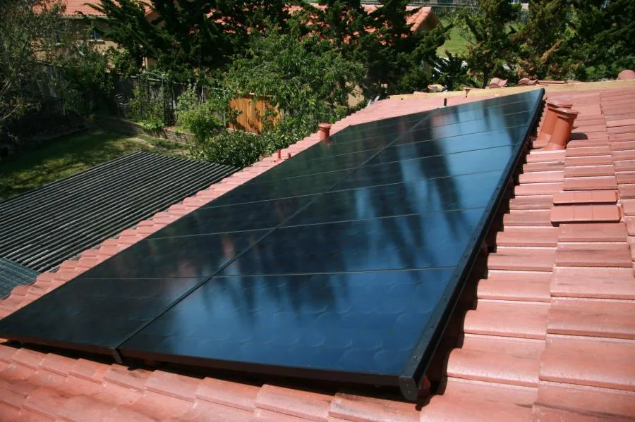 "Solar panels installed on a red tiled roof by Century Roof and Solar in Hayward, surrounded by trees."
