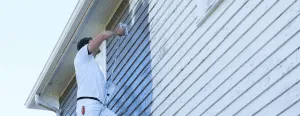 A person painting the exterior of a house, showcasing professional work by CertaPro Painters of Berkeley in Oakland.