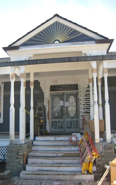 Front view of a classical-style house under renovation in San Francisco, with intricate woodwork and painting equipment visible.