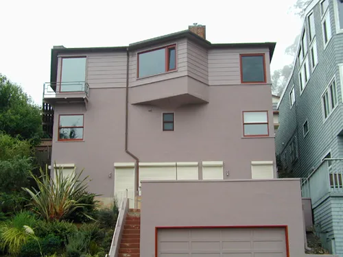 A modern two-story house in San Francisco painted in a muted purple-gray color with red trim accents, showcasing the work of Classic Shades Painting Co.