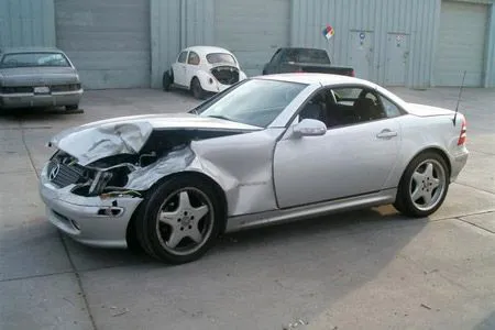A silver car with front-end damage parked outside Coelho's Body Repair and Auto Sales in Fremont.