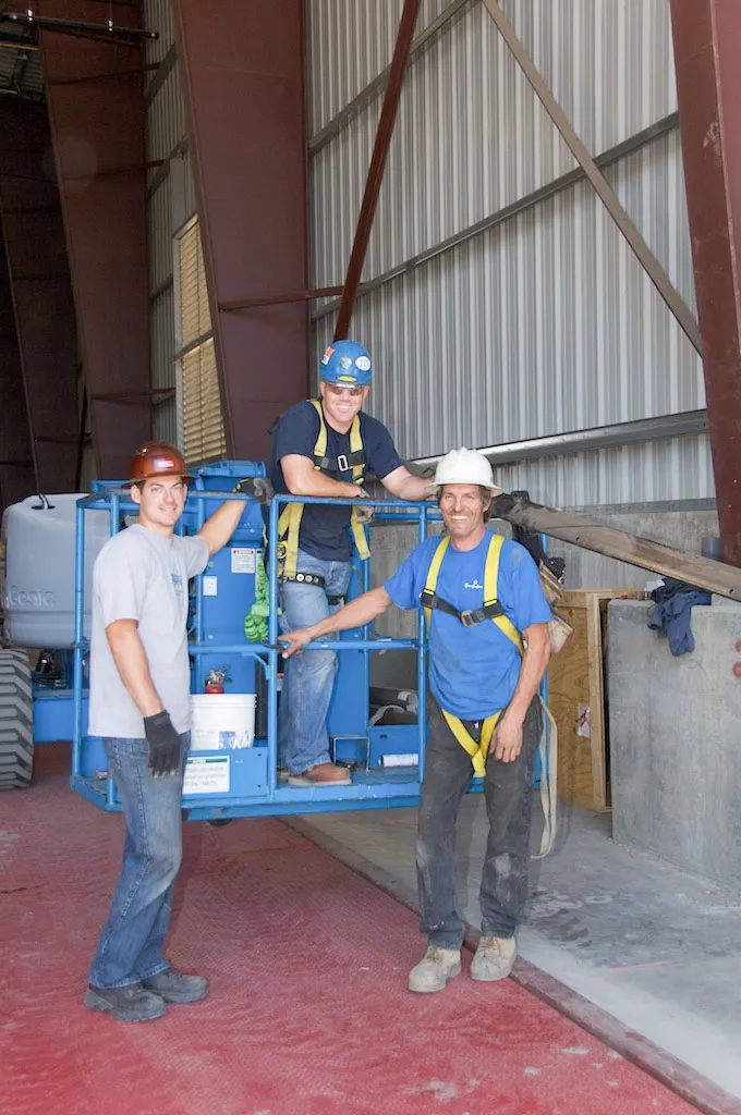 Three workers in safety gear standing next to industrial equipment inside a facility, representing Contra Costa Door in Concord.