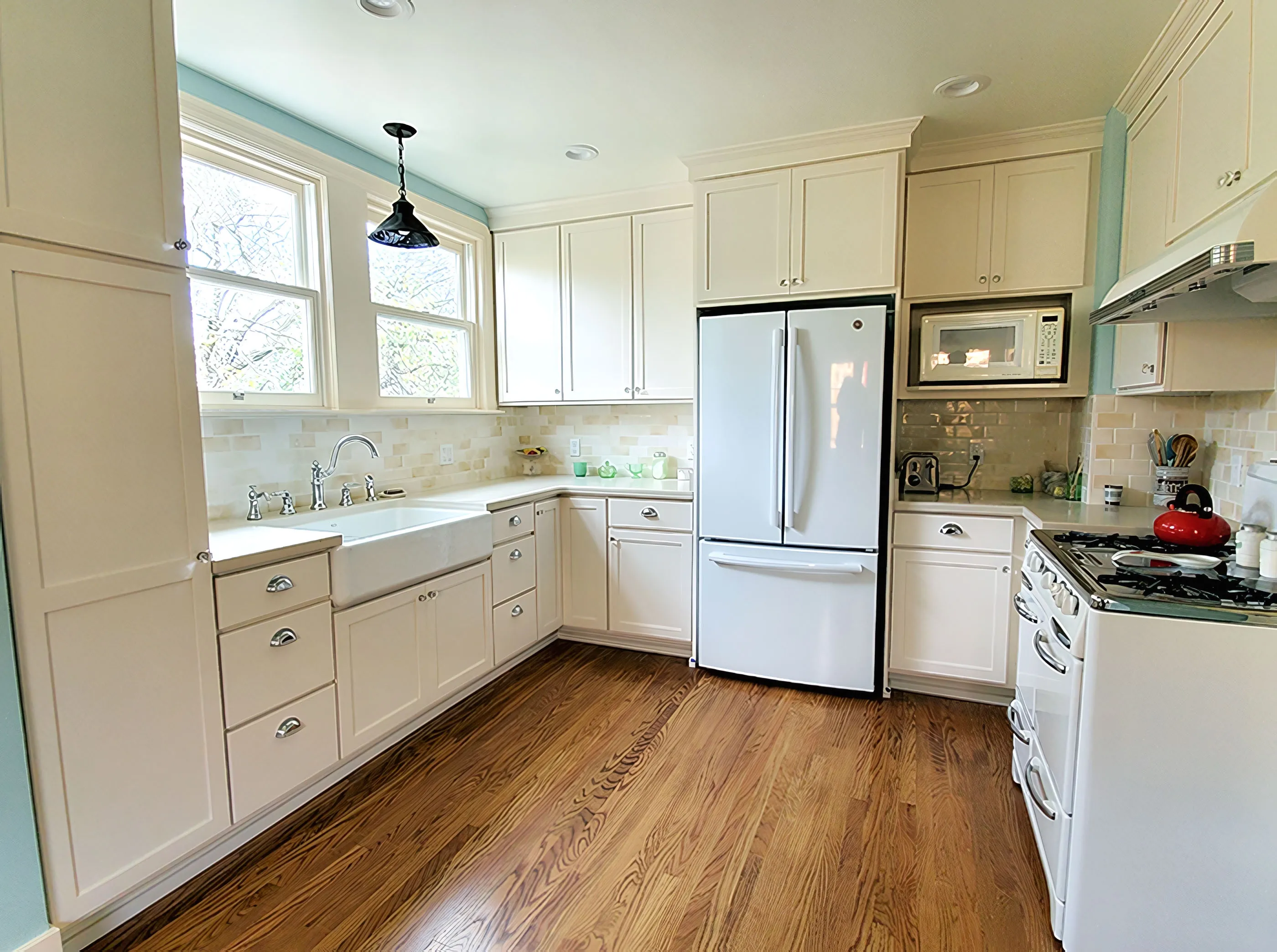 A modern kitchen with white cabinets, stainless steel appliances, and hardwood floor, designed by Cook's Kitchen & Bath, Inc. in Benicia.