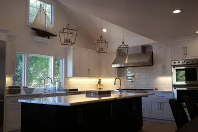 A modern kitchen with a large island, marble countertops, sleek cabinetry, pendant lights, and stainless steel appliances.