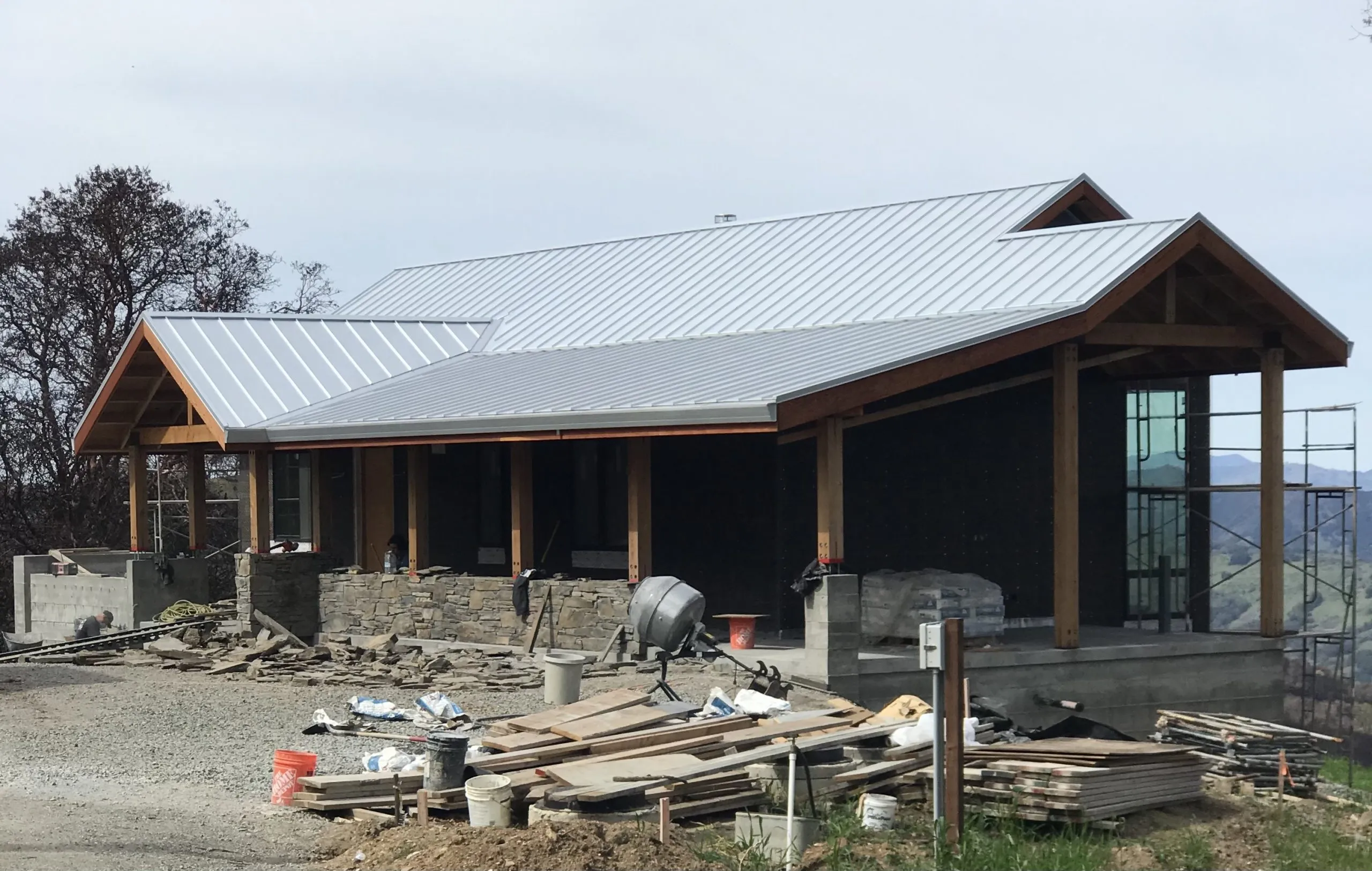 A modern house under construction featuring a newly installed metal roof by Crandall Roofing Inc. in Santa Rosa, surrounded by construction materials.
