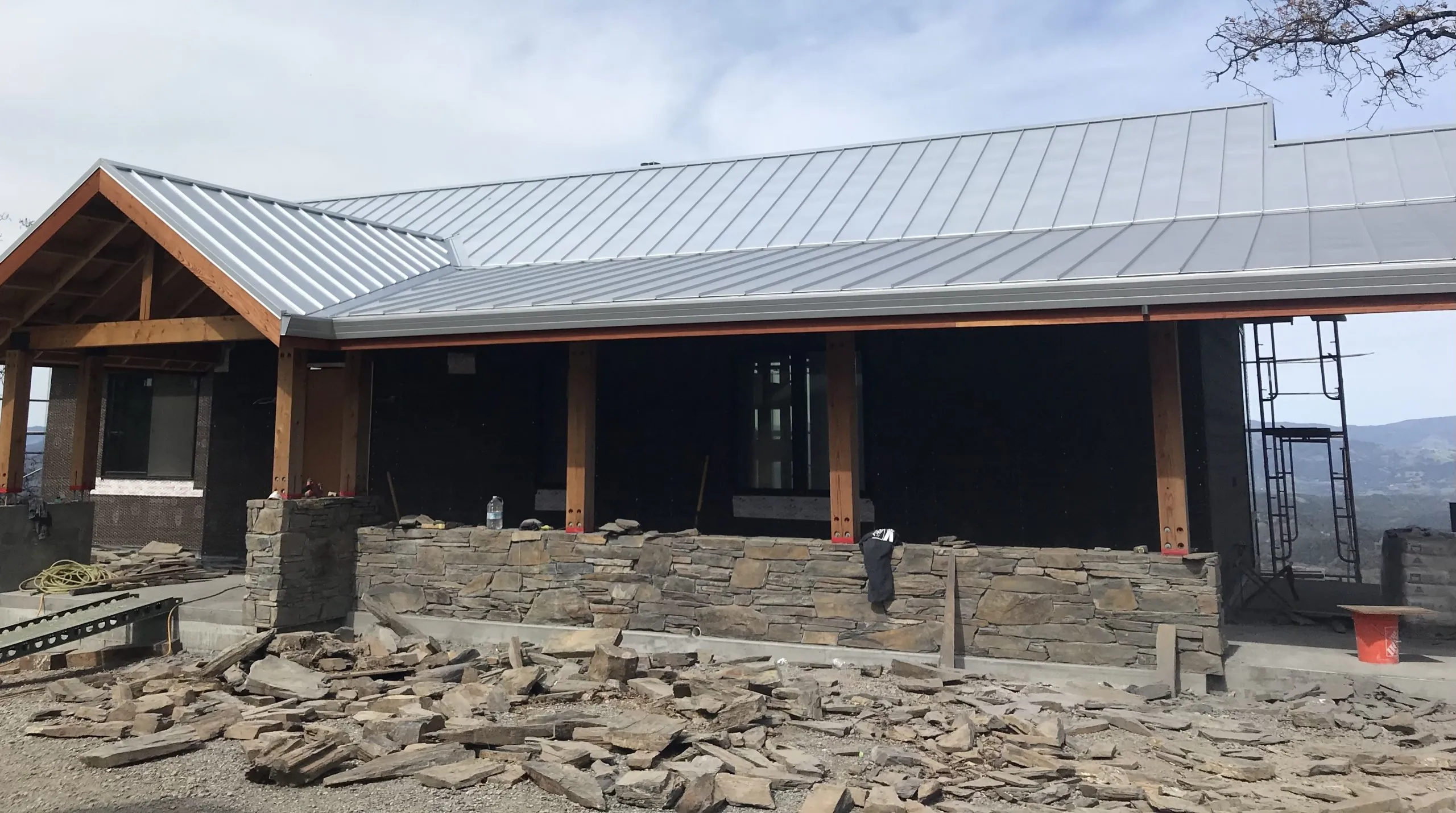 A building under construction with a metal roof and stone walls, showcasing the work of Crandall Roofing Inc. in Santa Rosa.