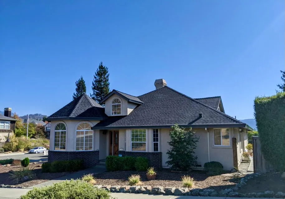 A house with a newly completed dark shingle roof by Crandall Roofing Inc., located in Santa Rosa, showcasing precise and expert craftsmanship.