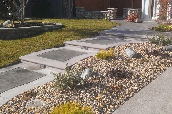 A landscaped garden in Vacaville featuring a modern stone pathway surrounded by gravel and greenery, designed by Creative Image Landscaping.