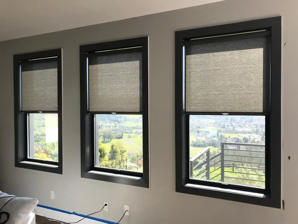 Three small windows with partial view shades, overlooking a landscape, designed by Creative Window Fashions.