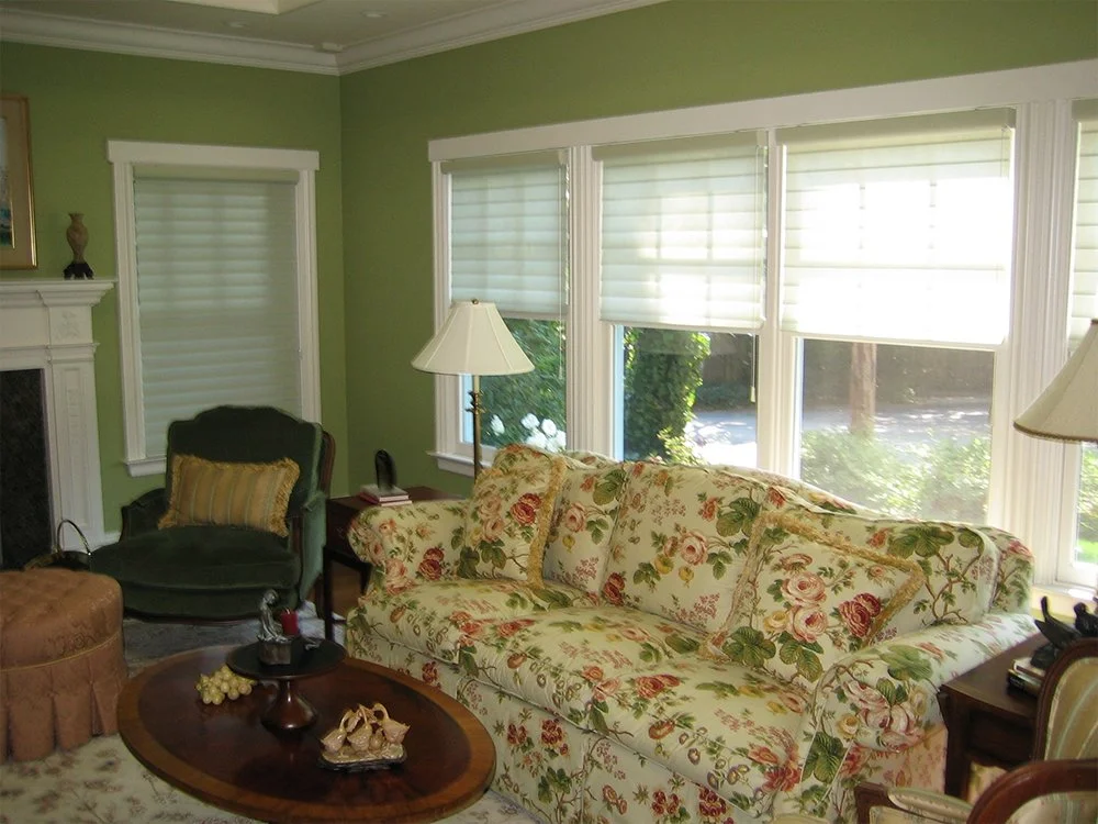 A cozy living room with floral-patterned furniture and soft, elegant blinds on the windows, designed by Creative Window Fashions in Rohnert Park.