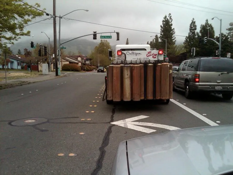 A Culligan Water truck carrying cylindrical tanks is seen driving on a road in Santa Rosa with trees and traffic lights in the background.