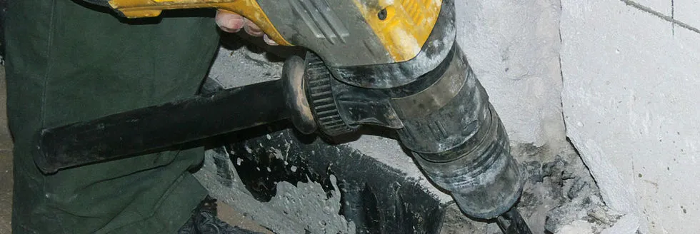 A person using a heavy-duty drill on a concrete surface, showcasing the equipment used by Curran Environmental Services Inc. in Petaluma for environmental management tasks.