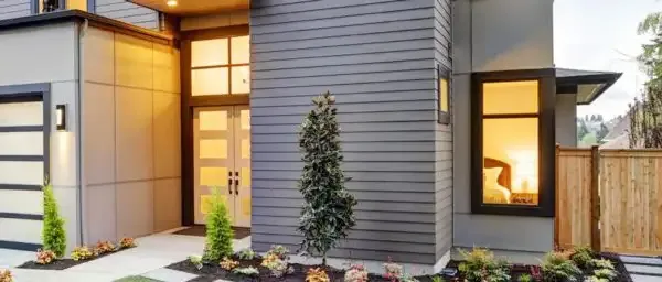 "Modern house exterior with sleek gray siding and warm lighting in Pleasanton, remodel by Custom Exteriors, Inc."