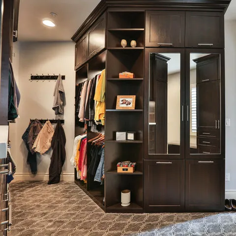 A modern, organized walk-in closet with dark wooden cabinets and shelves, designed by D.R. Domenichini Construction in Morgan Hill.