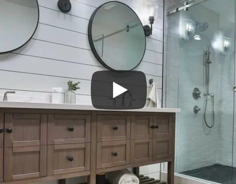 Modern bathroom with dual round mirrors, wooden vanity, and glass-enclosed shower designed by D.R. Domenichini Construction in Morgan Hill.