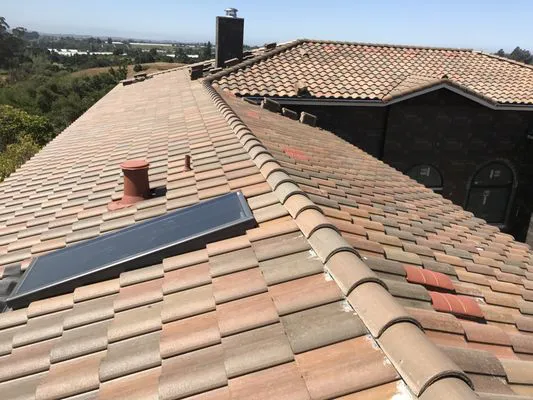 A tiled roof with a solar panel and a scenic view of Capitola, showcasing the workmanship of Daddario Roofing Company, Inc.
