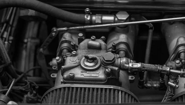 Black and white image of an engine component with detailed mechanics, showcasing precision engineering and mechanical expertise.