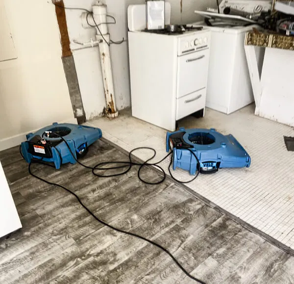 Two blue industrial fans operating on a kitchen floor during a restoration process, showcasing equipment used by Dansel Restoration Inc. in San Jose.