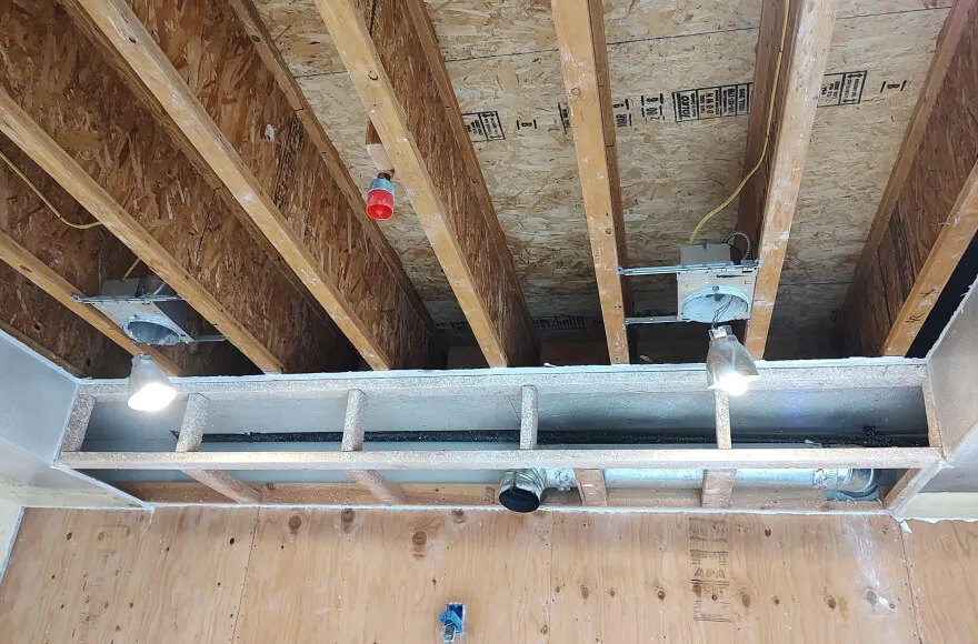 "Image of an unfinished ceiling with exposed wooden beams and electrical wiring, part of a restoration project by Dansel Restoration Inc. in San Jose."