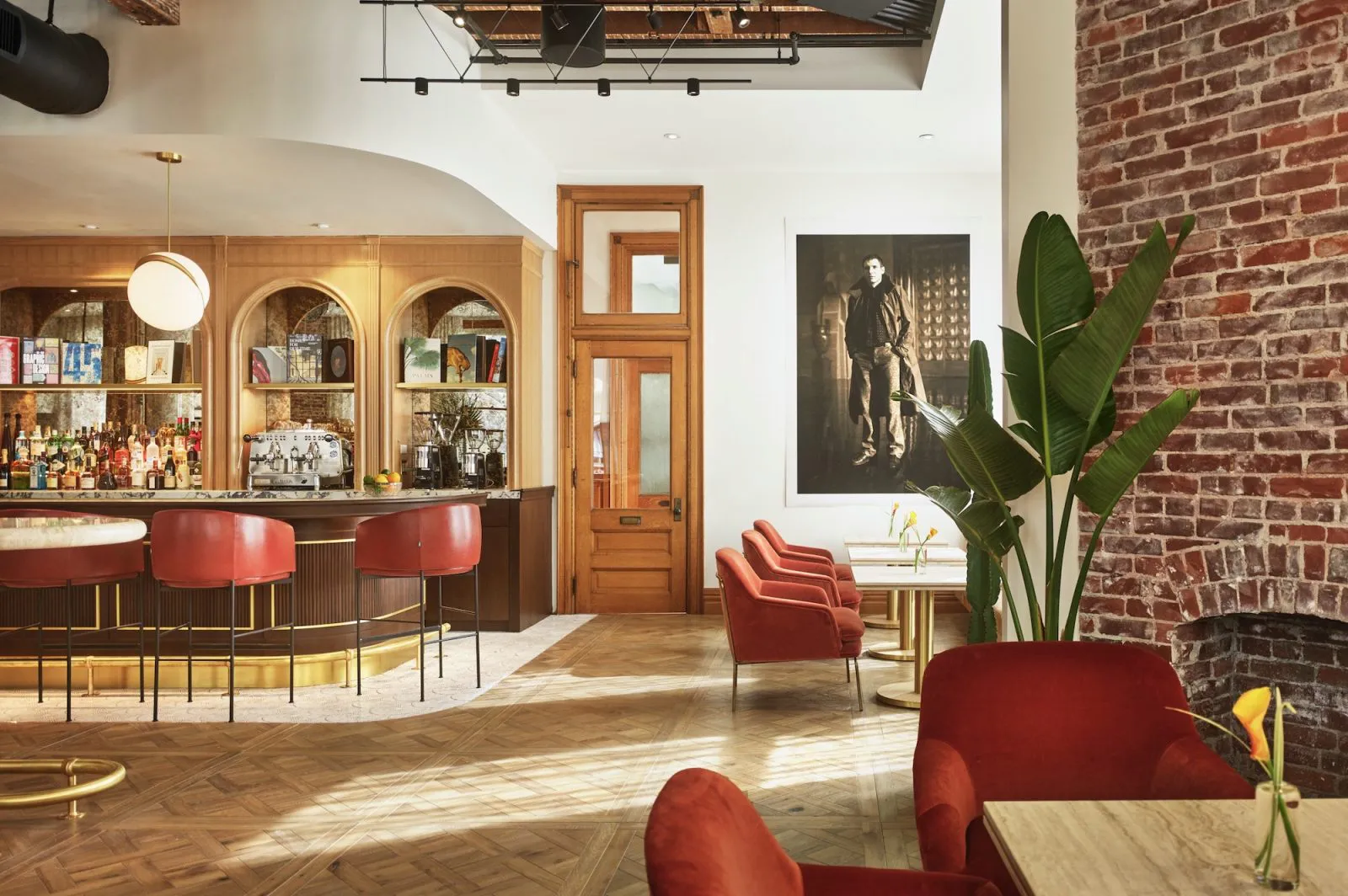 Interior of a stylish bar with red chairs, a wooden bar counter, and a large plant, showcasing the design work of Danville Hardwood Company in Danville.