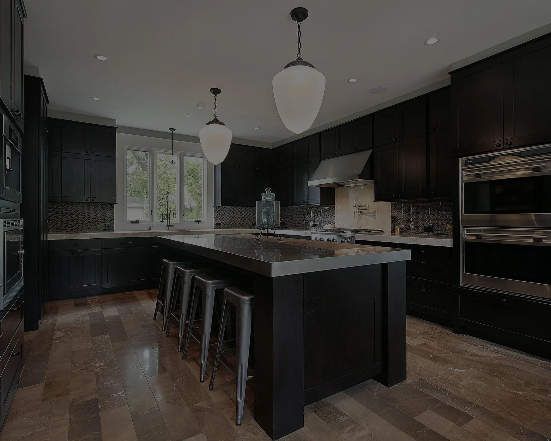 Modern kitchen with dark cabinets, a central island with bar stools, stainless steel appliances, and pendant lighting, remodeled by David Bianchi Home Repair, Inc., in Vacaville.