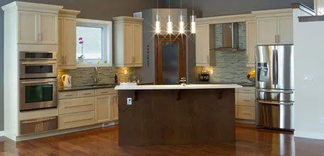 A modern kitchen with light cabinetry, a central island with dark wood, pendant lighting, stainless steel appliances, and a hardwood floor, designed by David Bianchi Home Repair, Inc. in Vacaville.