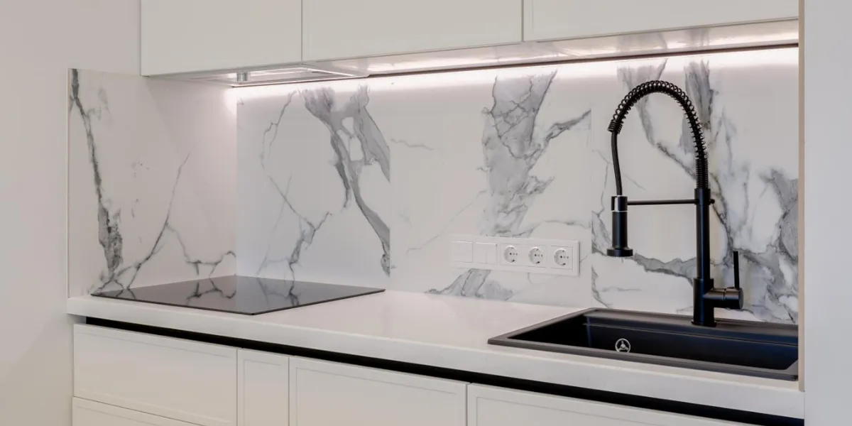 A modern kitchen featuring a sleek marble backsplash, an induction cooktop, and a black faucet with a sink, designed by Design Miter Tile in Campbell.