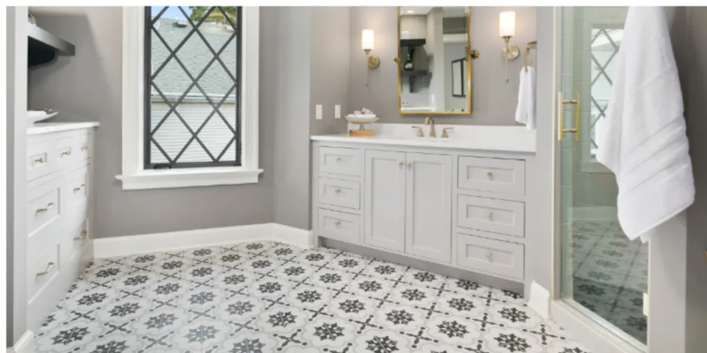 "A bathroom featuring intricate black and white patterned floor tiles, white vanity, and gold-accented fixtures."