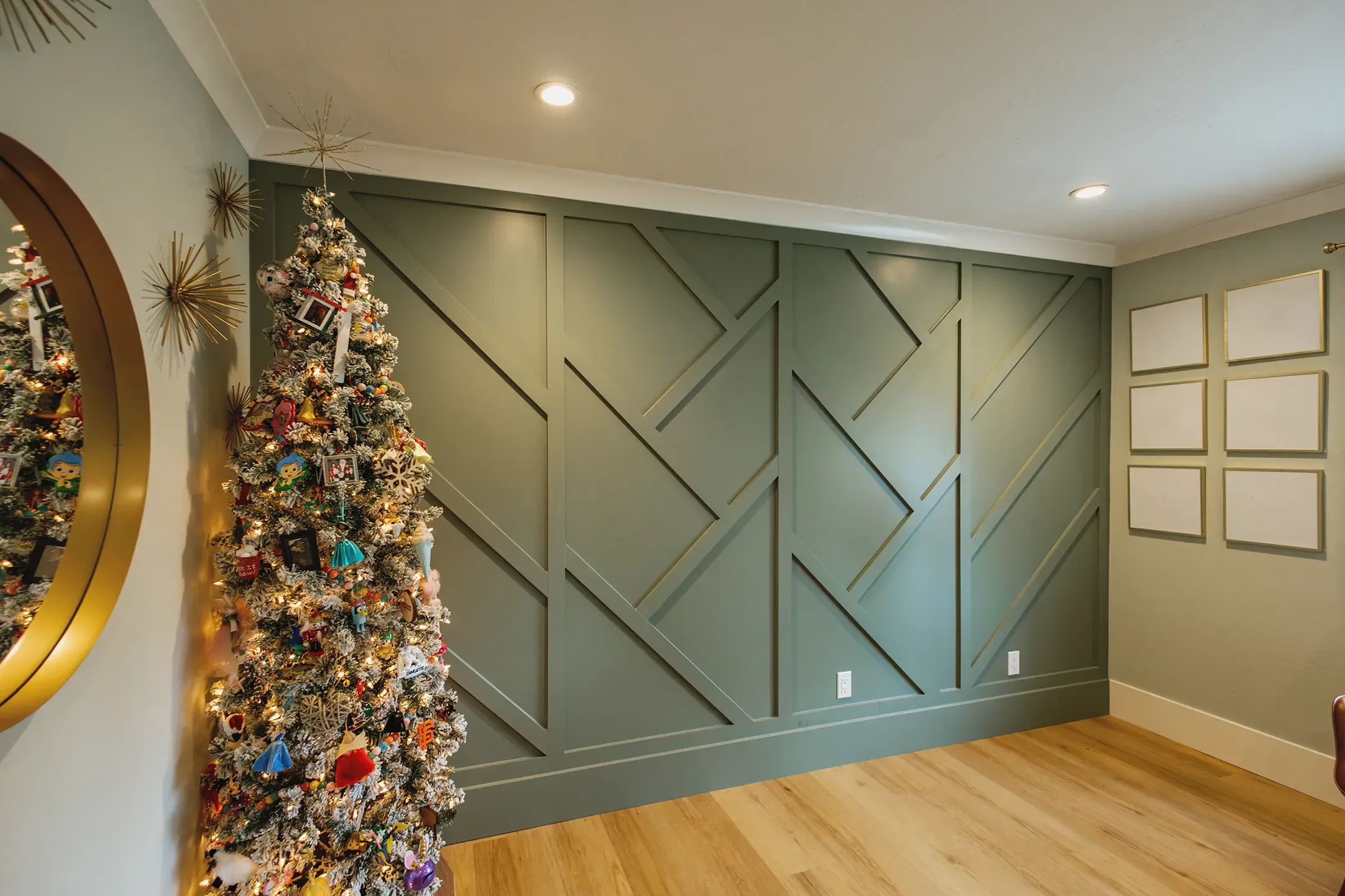 A decorated Christmas tree stands in a room with a geometric green accent wall and wooden floor, viewed from Devengenzo & Company in Lafayette.