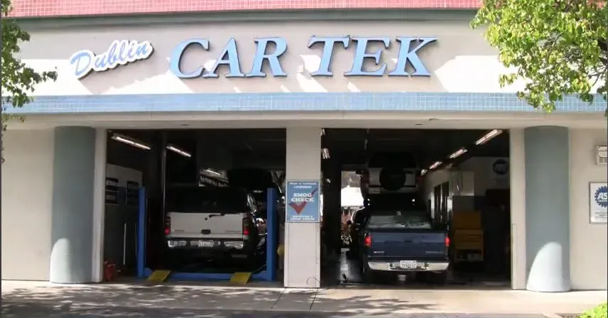 The exterior of Dublin Car Tek's auto repair shop in Dublin, showing two vehicles being serviced inside the garage.