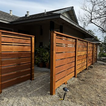 A modern wooden fence with horizontal panels installed in front of a house, showcasing the work of Duce Construction, Inc. in Walnut Creek.