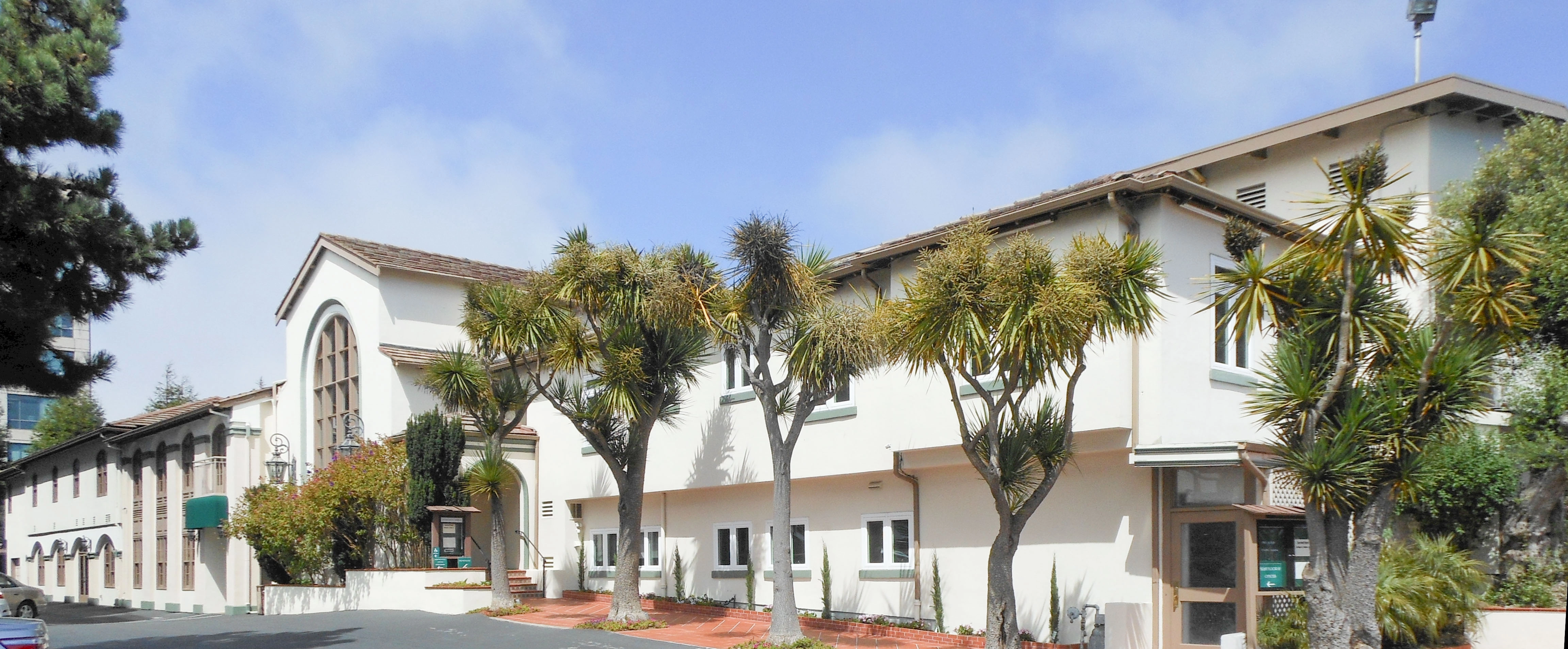 Exterior view of Duggan's Serra Mortuary in Daly City with palm trees lining the entrance.