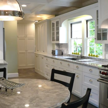 A modern kitchen with white cabinets, marble countertops, and stainless steel appliances, designed by Dutcher Construction in Sacramento.