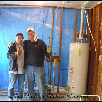 Two workers standing in a kitchen under renovation, with construction tools and a water heater visible, associated with Dutcher Construction in Sacramento.